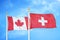 Canada and Switzerland two flags on flagpoles and blue cloudy sky