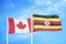 Canada and Uganda two flags on flagpoles and blue cloudy sky
