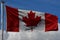 Canadian and British Columbian flags proudly waving against the blue sky.