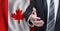 Canadian business, politics, cooperation and travel concept. Hand on flag of Canada background