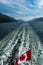 The Canadian flag flying in the wind at the back of ferry as the boat makes it way through the Inside Passage