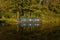 Canal barge narrow boat reflected in water surrounded by trees