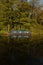 Canal barge narrow boat reflected in water surrounded by trees