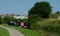 Canal boat owners enjoing summer sun as a cyclist passes by