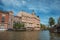 Canal with brick building, bascule bridge, restaurant and blue sky in Amsterdam.