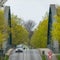 Canal bridge in arch construction with yellow and green flowering birches at the edge of the road made of grey asphalt