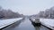 Canal in the city of with house boats on a cold winter day with embankments covered in snow Ghent