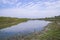 Canal with green grass and vegetation reflected in the water nearby Padma River