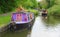 Canal narrowboat cruising past moored boat