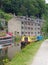 Canal running through hebden bridge with moored boats reflected in the water and stone buildings surrounded by trees