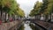 Canal running through an urban cityscape with cars parked along the banks