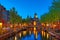 Canal and St Nicholas Church in Amsterdam at twilight, Netherlands. Famous Amsterdam landmark near Central Station.