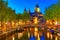 Canal and St Nicholas Church in Amsterdam at twilight, Netherlands. Famous Amsterdam landmark near Central Station