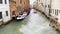 Canal in Venice street between houses with floating motorboat and parked boats