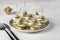 Canape with salted herring, olives and cucumber on white bread toasts on gray background
