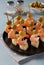 Canape with shrimp, pineapple and olives - festive bright appetizer on blue background