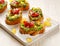 Canapes with the addition of guacamole, tomatoes, onion, chili peppers and fresh coriander