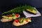 Canapes, avocado wedges and tomato slices are laid out on a piece of baguette, avocado halves and fresh dill sprigs are on a