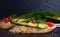 Canapes, avocado wedges and tomato slices laid out on a piece of baguette, black background