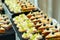 Canapes with cheese and grapes and sandwiches with bacon and cabbage and tomatoes with olives on a skewer on a buffet table