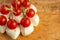 Canapes of mozzarella and cherry tomatoes on wooden plate