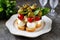 Canapes of mozzarella, green olives, cherry tomatoes, basil on croutons of white bread.