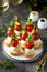 Canapes of mozzarella, green olives, cherry tomatoes, parsley on croutons of white bread.