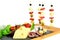 Canapes of olives, chorizo, salami, cheese and apple on the wooden sticks. Cheese, fuet, green herbs and tomatoes cherry on the