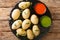 Canarian Wrinkly Potatoes Papas Arrugadas with a mojo rojo and mojo verde sauces close up in the plate. Horizontal top view