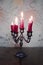 Candelabrum with red burning candles and floral tapestry in the background