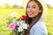 Candid adorable young woman in field with flower bouquet at spring season