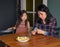 Candid asian family mom and daughter in kitchen at home, mother gives treat to girl at table, cozy apartment lifestyle