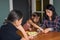 Candid asian family mom and two daughters in kitchen at home, mother gives treat to girl at table, apartment lifestyle