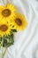 Candid authentic Yellow sunflowers bouquet on fabric white background. Background with bouquet of yellow sunflowers on