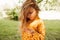 Candid closeup portrait of cute little girl have seriously face during looking to her fingers, osing at nature background.