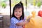 Candid. Happy Asian girl sweet smile is sitting on a yellow rocking horse spring. Child send sweet smiles to their families.