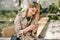 Candid outdoors image of young beautiful woman writing messages on smartphone, sitting outdoor in the city at sunny day.