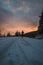 Candid portrait of a man in winter clothes standing at the end of a path watching the sunrise in the snowy area of Stare Hamry