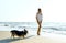 Candid shoot laughing girll at summer beach with pet Corgi dog, standing in front sea