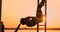 Candid shot of real healthy and fit woman performing hanging leg raises on outdoor fitness station in sunset at beach