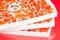 Candied pumpkin on the tray for drying fruits, on red background. Homemade sweetness of dried fruit.