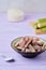 Candied rhubarb, sprinkled with powdered sugar, in a ceramic plate on a purple wooden background. Preparations, conservation.