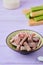 Candied rhubarb, sprinkled with powdered sugar, in a ceramic plate on a purple wooden background. Preparations, conservation.