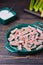 Candied rhubarb, sprinkled with powdered sugar, in a ceramic plate on a purple wooden background. Preparations, conservation.