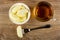 Candies in shape of bananas in bowl, cup with tea, candy strung on fork on wooden table. Top view