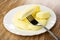 Candies in shape of bananas in plate, candy strung on fork on table