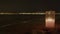 Candle aglow with blurred city lights on beach