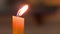 A candle burns with a yellow flame in the church, the flame sways, blurred background