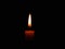 Candle flame on black background. Single lit candle with quite flame. Dramatic burning candle flame on a black background with