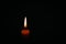 Candle flame on black background. Single lit candle with quite flame. Dramatic burning candle flame on a black background with